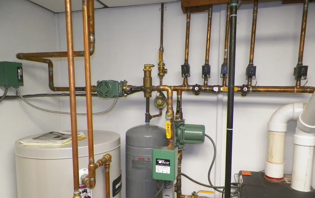 A boiler room with copper near-boiler piping, zone valves, circulator pumps and an expansion tank